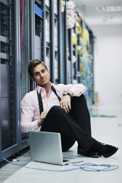 Businessman with laptop in network server room - Foto, afbeelding
