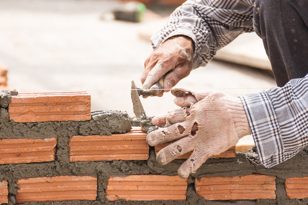 Bricklayer working in construction site of a brick wall - Φωτογραφία, εικόνα