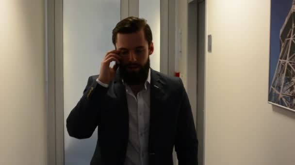 young handsome man with full-beard (hipster) walks and phone in the office - steadicam - Záběry, video