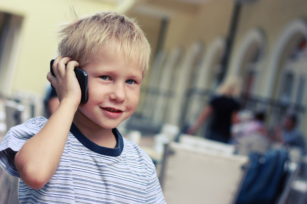 Garçon parle à un téléphone portable dans un supermarché
. - Photo, image