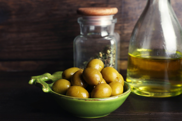Olives With oil on table on wooden background - Foto, Imagen