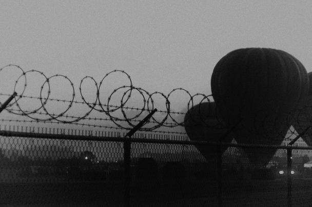 зернистое драматическое изображение воздушных шаров за забором из колючей проволоки
 - Фото, изображение
