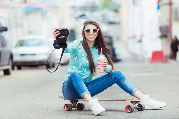 Beautiful young woman posing with a skateboard, fashion lifestyle at sunset - Photo, Image