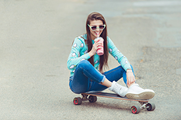 schöne junge Frau posiert mit einem Skateboard, Mode-Lifestyle bei Sonnenuntergang - Foto, Bild