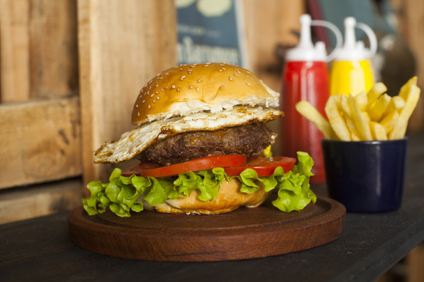 Hamburger z frytkami na drewnianym stole - Zdjęcie, obraz
