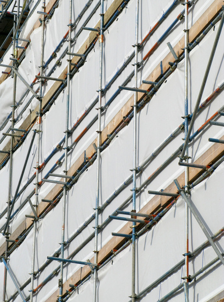 Close up building covered by scaffolding and white tarpaulin. - Photo, Image