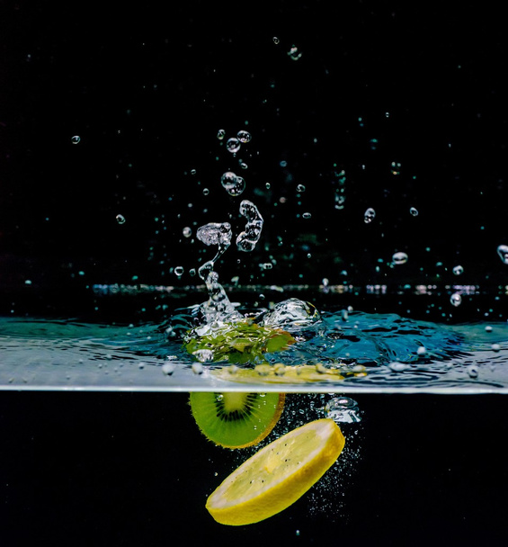 Limone e kiwi in acqua, isolati su fondo nero
 - Foto, immagini
