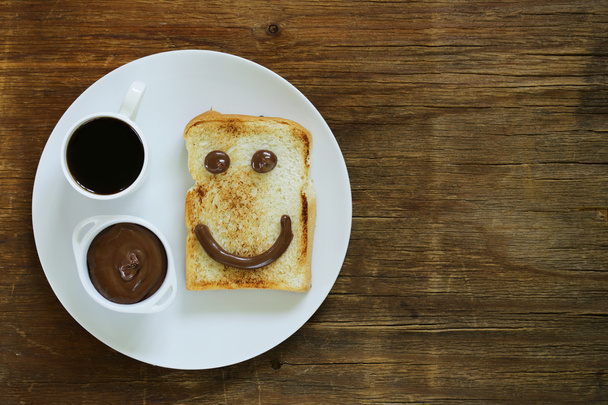 朝食 (トースト、チョコスプレッド、コーヒー皿の上に変な顔を提供) - 写真・画像