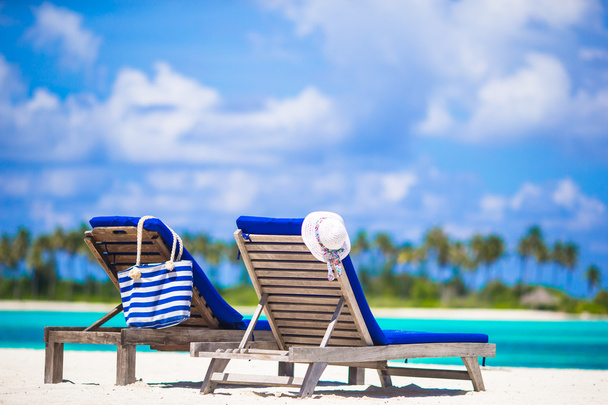 Lounge stoelen met zak en hoed op tropische witte strand - Foto, afbeelding