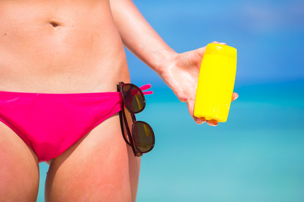 Jeune femme appliquant avec de la crème solaire sur la plage blanche
 - Photo, image