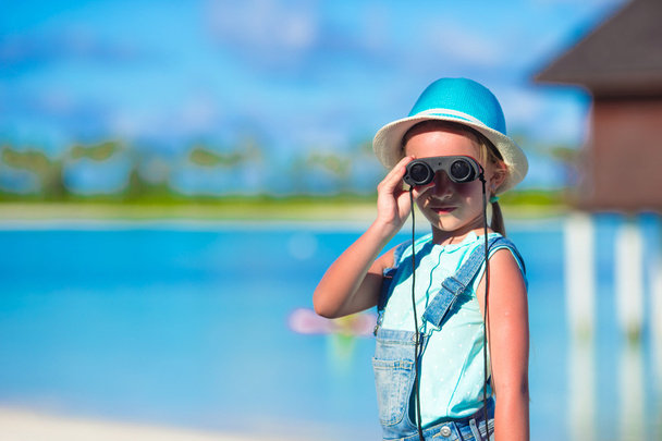 Little girl looking through binoculars in sunny day during summer vacation - Photo, Image