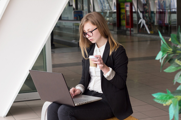 Young business woman with a laptop drinking coffee - 写真・画像