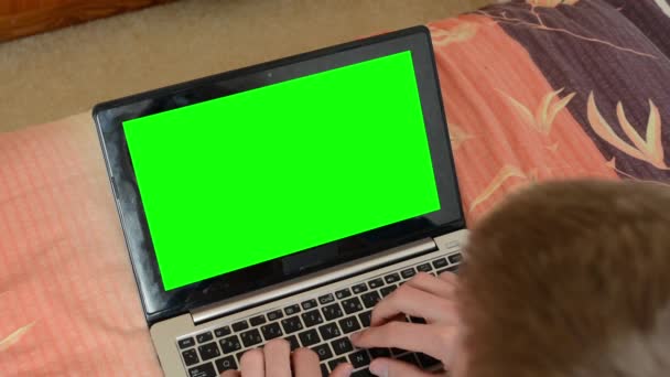 hombre acostado en la cama y trabaja en el ordenador portátil (portátil
) - Imágenes, Vídeo