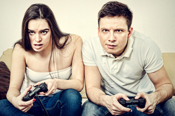  couple assis dans le salon et jouer à des jeux vidéo sur console o
 - Photo, image