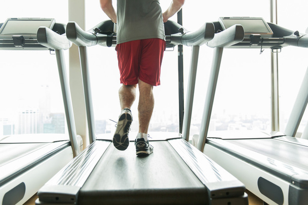 close up of male legs running on treadmill in gym - Fotoğraf, Görsel