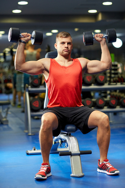 young man with dumbbells flexing muscles in gym - Φωτογραφία, εικόνα