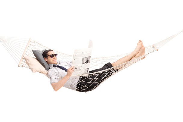 Relaxed man reading newspaper in a hammock  - Photo, Image