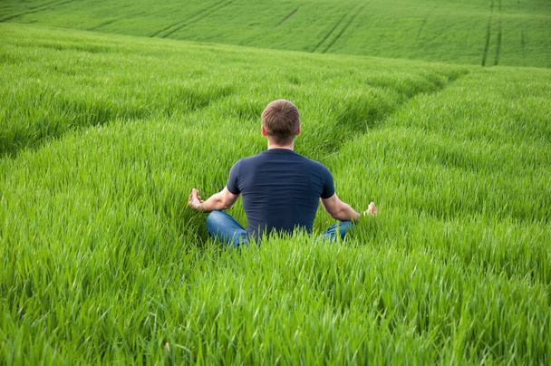 Adam yeşil çayır ortasında oturur - Fotoğraf, Görsel