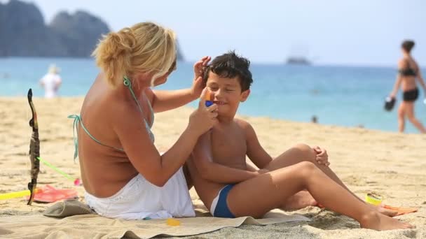 mother applying sunscreen to son - Filmagem, Vídeo