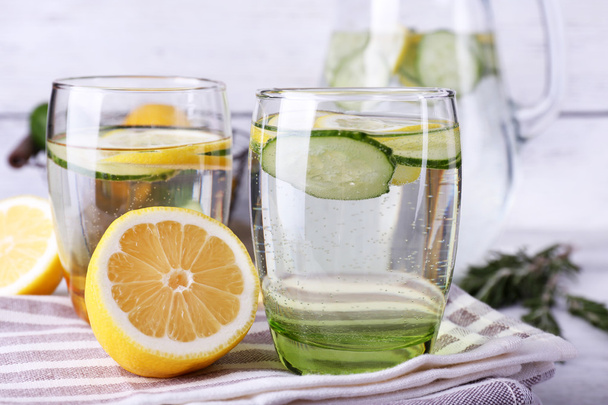 Fresh water with lemon and cucumber in glassware on wooden table, closeup - Фото, зображення
