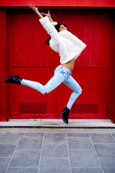 nainen hyppää punaisen oven taustalla
 - Valokuva, kuva