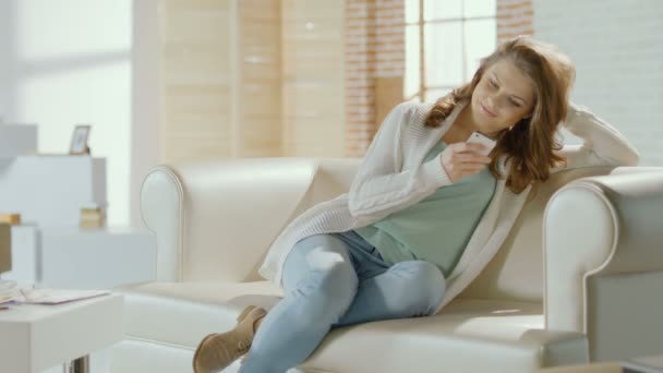 Beautiful girl typing message, chatting on smartphone at home - Filmagem, Vídeo
