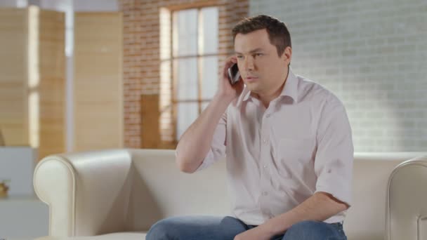 Young man discussing business problems in phone call at home - Záběry, video