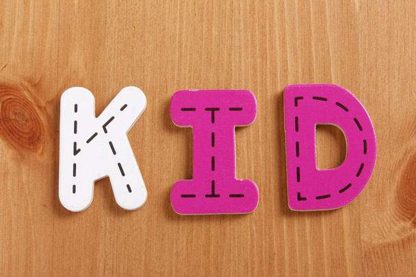 KID, spell by woody puzzle letters with woody background - Foto, immagini
