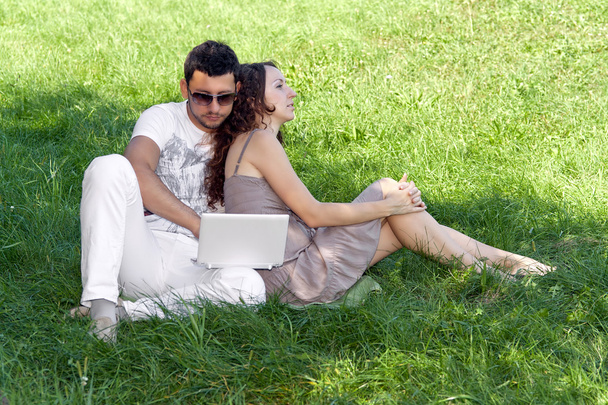 Jovem com laptop e menina na grama verde
 - Foto, Imagem