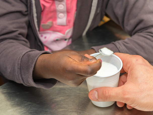 Ręce afro amerykańskich studentów podstawowej biorąc cukru z tworzyw sztucznych - Zdjęcie, obraz