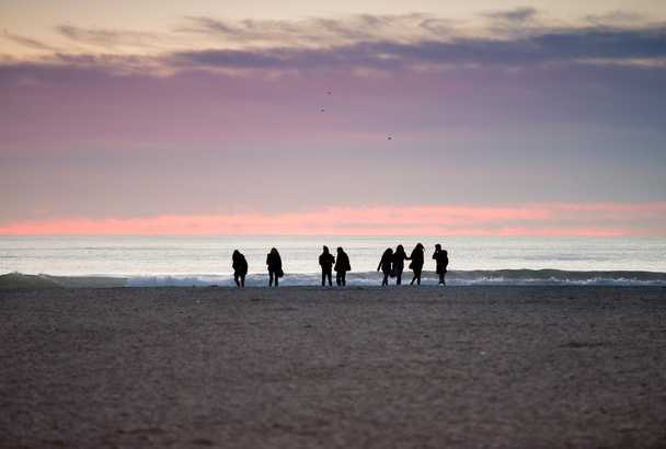 Silhouettes de personnes sur la plage au crépuscule
 - Photo, image