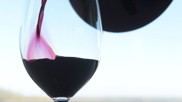 Glass being filled with red wine with carafe on white background - Footage, Video