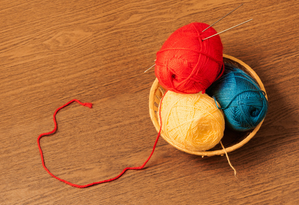 Skeins of yarn in a basket with knitting needles - Fotó, kép