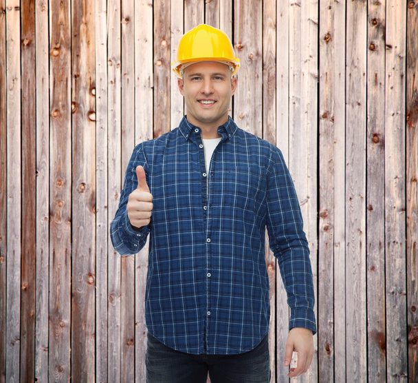 smiling male builder in helmet showing thumbs up - Foto, Bild