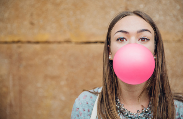 Joven adolescente soplando goma de mascar rosa
 - Foto, Imagen