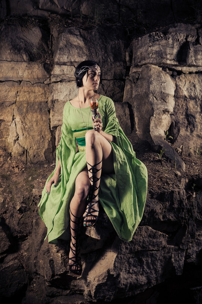 schöne Elfenprinzessin trinkt einen Wein auf dem Felsen. - Foto, Bild