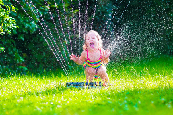 Petite fille jouant avec arroseur d'eau de jardin
 - Photo, image