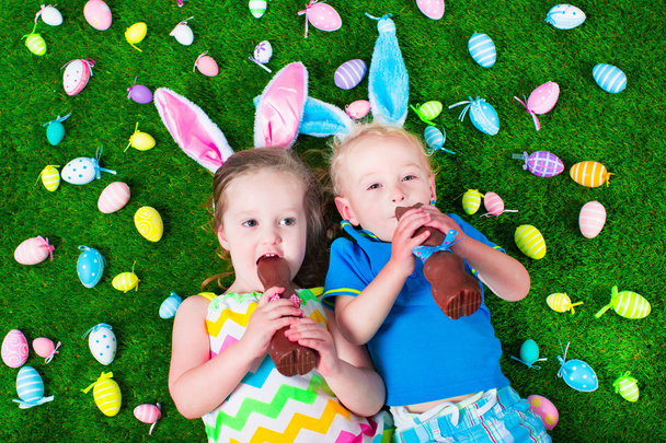 Enfants mangeant du lapin en chocolat sur la chasse aux œufs de Pâques
 - Photo, image
