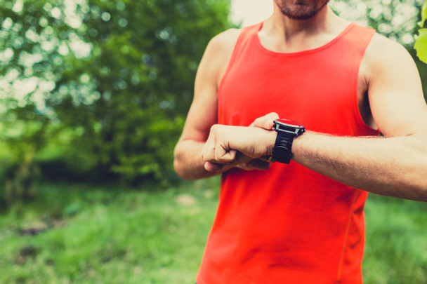 Runner looking at sport watch smartwatch - Photo, image
