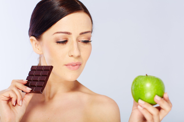 woman with a apple and chocolate in her hand - Foto, Bild