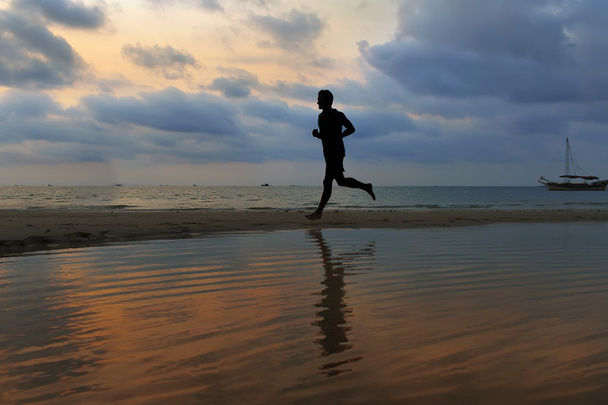 atleta corre ao longo da praia de areia com espelho na água e o
 - Foto, Imagem