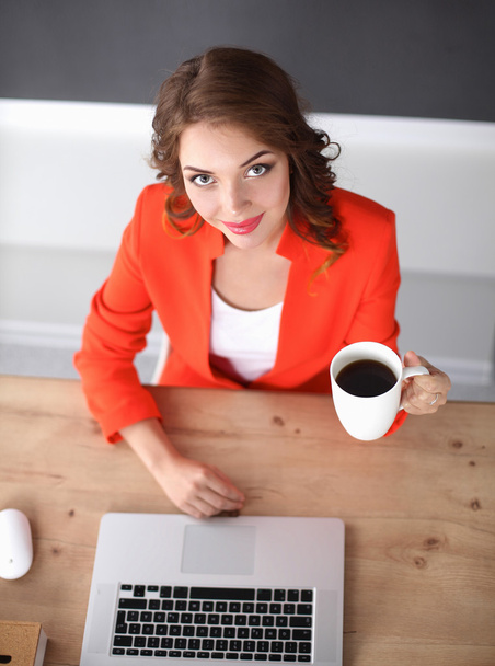 Attractive woman sitting at desk in office, working with laptop computer - Photo, image