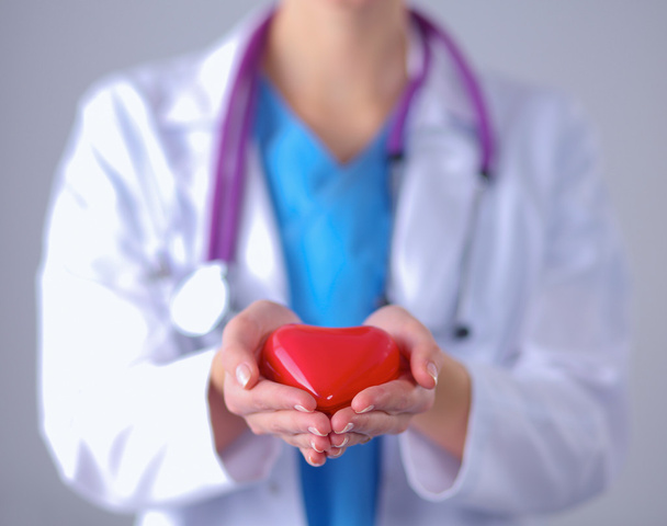 病院に立っている赤い心臓を持った若い女性医師 - 写真・画像