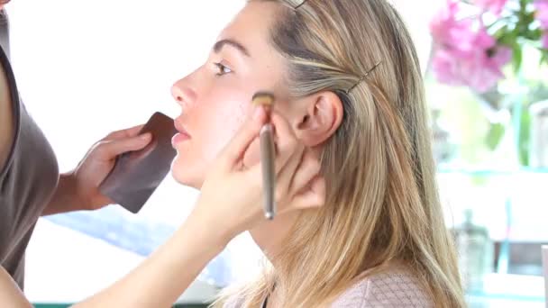 καλλιτέχνης μακιγιάζ εφαρμογή καλλυντικά τονικό ίδρυμα στο πρόσωπο χρησιμοποιώντας πινέλο - Πλάνα, βίντεο