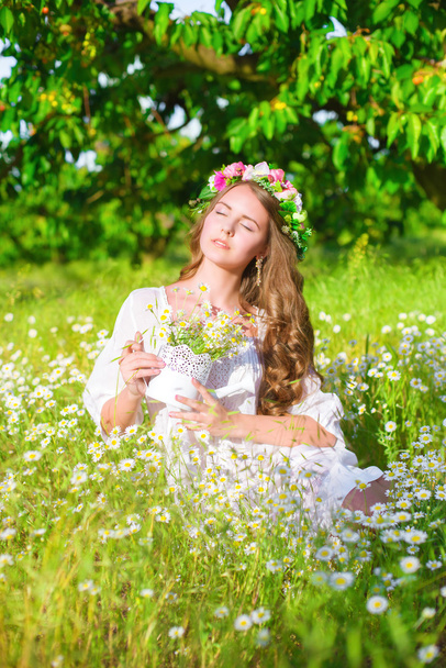 The girl with long hair wearing a crown of daisies on the field - Foto, immagini