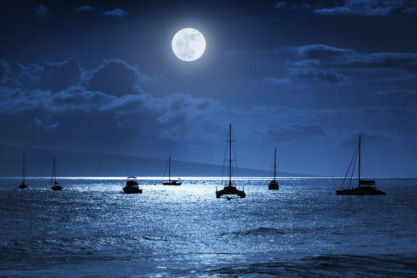 This dramatic photo illustration of a nighttime sky over a calm ocean scene in Maui, Hawaii with brightly lit clouds, a large, full, Blue Moon, calm waves, and sparkling reflections would make a great background for many travel or vacation uses - Photo, Image