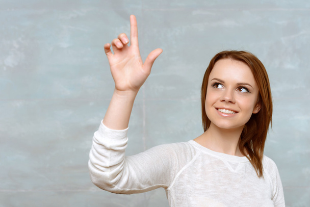 Young woman pointing upwards with her index finger. - Foto, Imagen