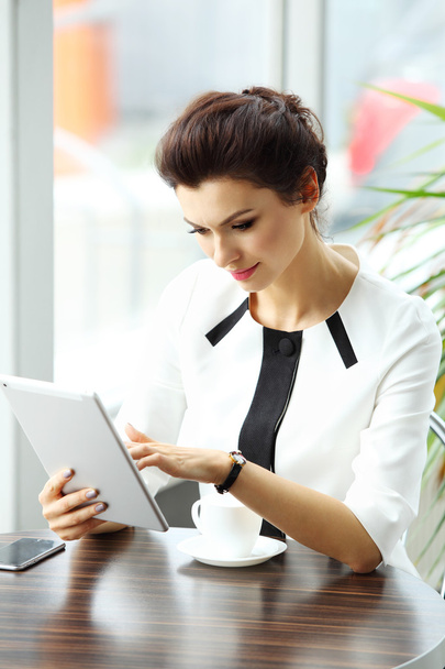 Pensive businesswoman reading an article on tablet computer in a - Photo, image