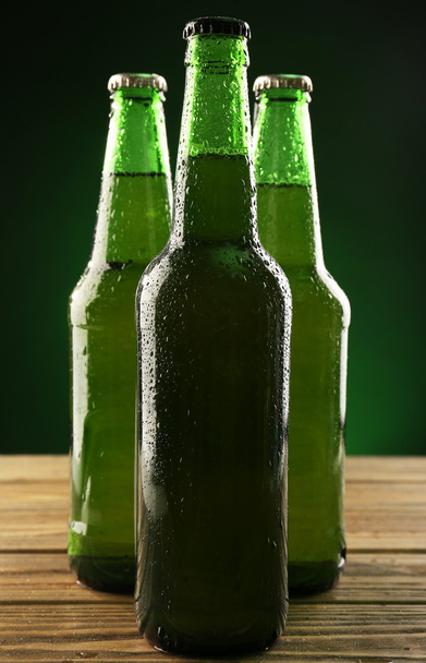 Glass bottles of beer on dark green background - 写真・画像