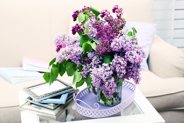 Beautiful lilac flowers in vase on table - 写真・画像